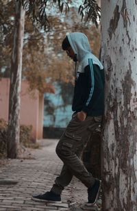 Side view of man standing on tree trunk