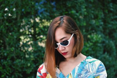 Close-up of woman wearing sunglasses against plants