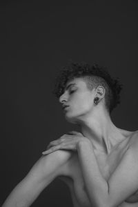 Portrait of young man looking away against black background