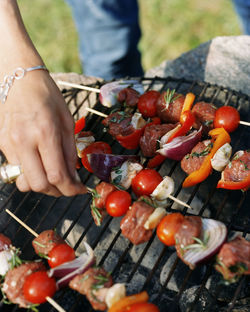 Woman checking kebabs on barbecue