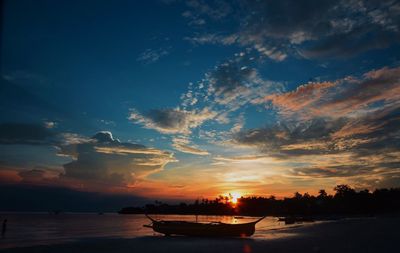 Silhouette boats moored on sea against sky during sunset