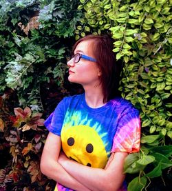 Young woman looking away while standing amidst plants