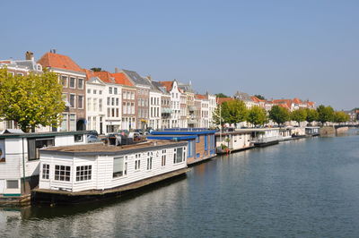 Buildings by river against clear sky