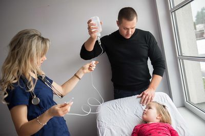 Doctors adjusting iv drip for girl at hospital