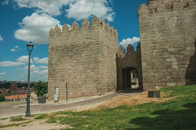 Road going through carmen gateway in the stone city wall with towers in avila, spain.