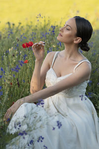 Side view of young woman standing amidst plants