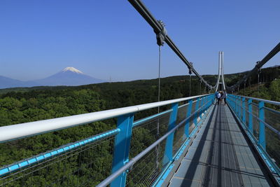 Footbridge over land against clear blue sky