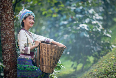 Smiling woman standing in basket against plants