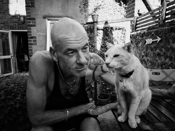 Close-up of thoughtful man with cat sitting outdoors