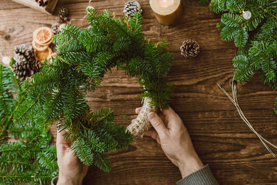 Top view of male hands making  christmas wreath from natural spruce branches and various decorations