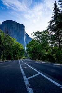 Road by trees against sky