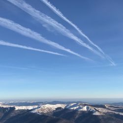 Scenic view of vapor trail in snow against sky