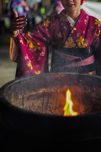 Midsection of woman standing by fire pit in temple 