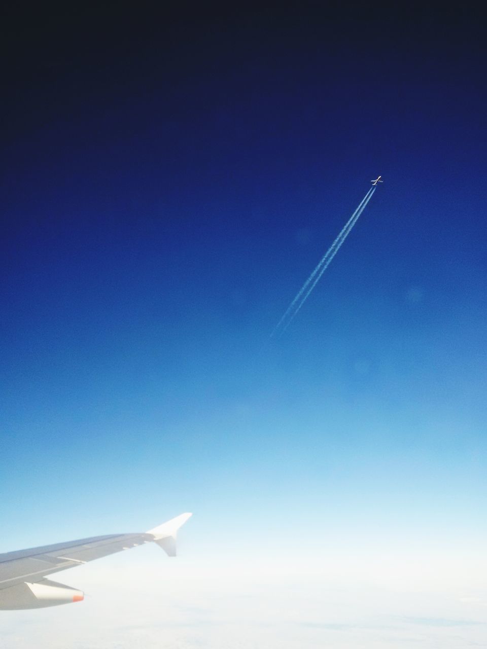 AIRPLANE FLYING OVER VAPOR TRAIL IN SKY