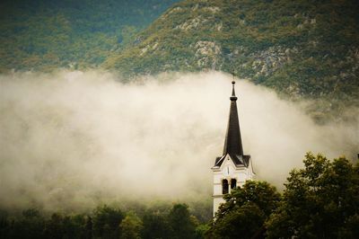 Tower amidst trees and buildings against sky