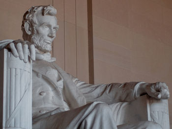 Statue of man sitting by wall