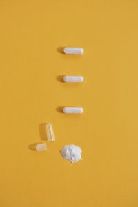 High angle view of pills on yellow background