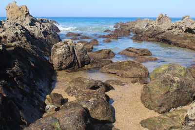 Rocks on beach against clear sky