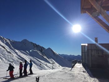 People on snow covered landscape against clear sky