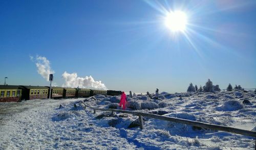 Scenic view of snow covered field against sky on sunny day