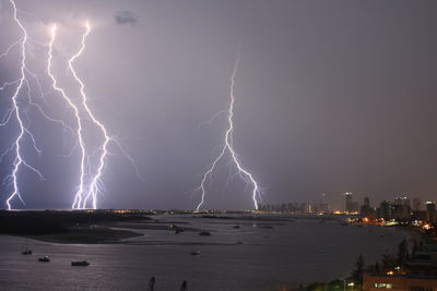 Lightning over cityscape against sky at night