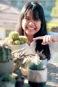 Portrait of smiling girl by potted plant outdoors
