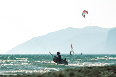 Person paragliding over sea against sky