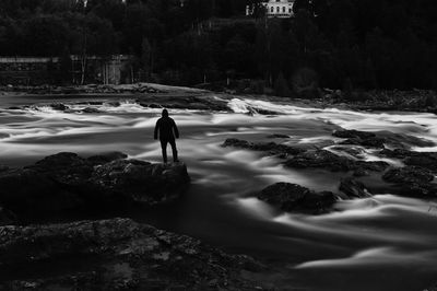 Silhouette man standing on rocks at shore