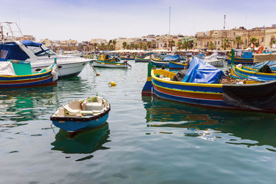 Boats moored at harbor against sky