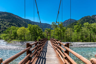 Footbridge over river against sky