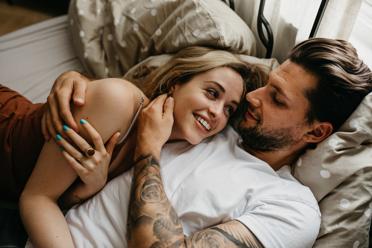 High angle view of loving young couple lying on bed at home