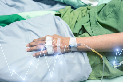 Digital composite image of person with iv drop and pulse trace on bed at hospital 