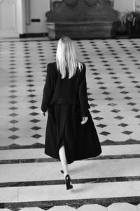 Rear view of woman walking tiled floor