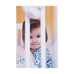 Portrait of cute baby girl in crib at home
