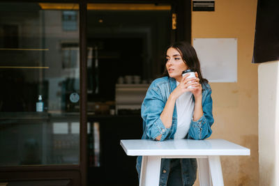 Full length of beautiful woman drinking glass on table