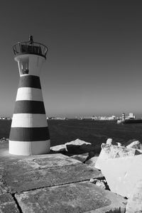 Lighthouse by sea against clear sky
