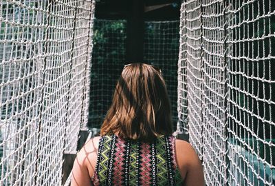 Rear view of woman standing amidst netting