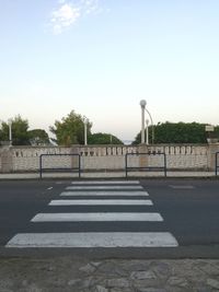 Street by footpath against sky in city