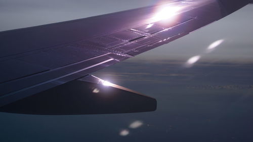 Close-up of airplane wing against sky during sunset