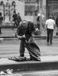 People on sidewalk in city inspecting trash bag