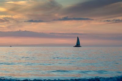 Sailboat in sea against sky during sunset