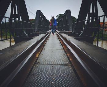 Rear view of man walking on footbridge