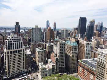 High angle view of urban skyline against cloudy sky