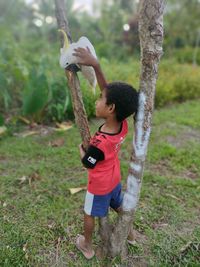 Full length of boy standing by tree