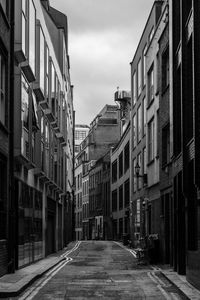 Empty road amidst buildings in city