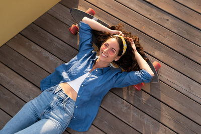 Carefree smiling woman on skateboard relaxed and happy. trendy girl skateboarder lying on longboard