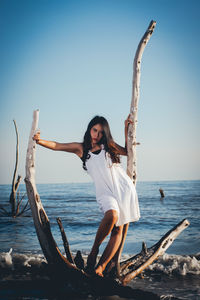 Woman with arms raised on beach against clear sky
