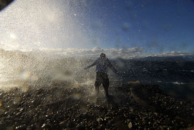 Man standing in sea against sky during winter