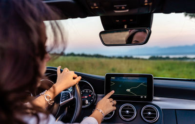 Young girl driving car using navigation system on electronic dashboard building route to destination 