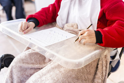 Disabled man with paper and pencil sitting on wheelchair